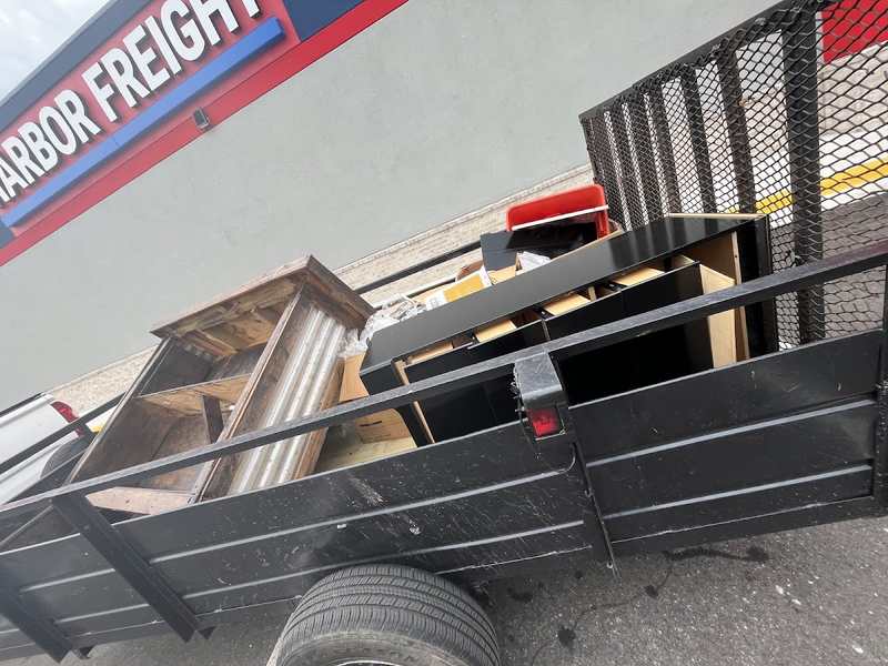 Utility trailer loaded with furniture and bulky household items.